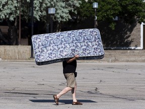 Greg Babko carries a mattress for a block in order to avoid the long line of cars coming into Northlands Coliseum for a Big Bin event on Saturday, July 10, 2021. The City of Edmonton is hosting Big Bin events for household items that can’t be set out for regular waste collection. Seven weekend events will be held in various locations throughout the City. Greg Southam-Postmedia