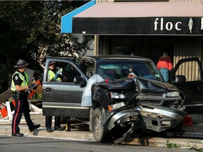 Police work at the scene of a single-vehicle collision that shut down the intersection of Jasper Avenue and 124 Street  in Edmonton on Monday, July 26, 2021.
