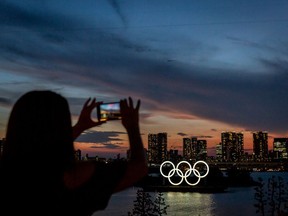 A woman takes photographs of Olympic rings at sunset on July 21, 2021 in Tokyo, Japan.