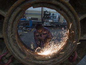 A worker works on a part from a rock crusher at Universe Machine, an Edmonton manufacturing company. File photo.