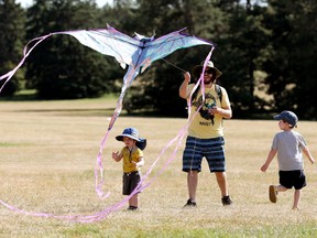 Brandon Girard and his son's Hudson Girard, 5, and Beck Girard, 2, fly a dragon kite in Edmonton's Hawrelak Park, Monday Aug. 9, 2021.