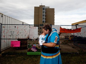 Lorelei Mullings holds her three week-old grandson Micah Mindus-Morin on the grounds of the former Charles Camsell Indian Hospital, in Edmonton, Monday Aug. 9, 2021. Mullins is a co-organizer of a protest that has been on site nearing 50 straight days, to bring awareness to the discovery of over 5,000 unmarked graves at Canada's former residential school sites.