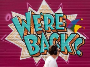 Artwork reading “We’re Back!” is seen on the garage door of the Backstage Theatre on the Edmonton International Fringe Festival grounds as setup continues in Old Strathcona on Wednesday, Aug. 11, 2021. Together We Fringe runs in person and online from August 12 22, 2021.