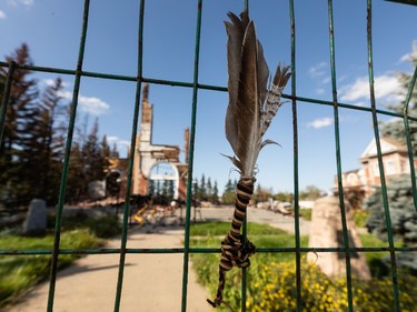 Feathers are seen pinned to a fence at the site of St. Jean Baptiste Church in Morinville, north of Edmonton, on Wednesday, Aug. 25, 2021. The church burned down on June 30 and the fire is under investigation. Photo by Ian Kucerak