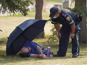 Emergency medical personnel speaks with a man who seemed to have suffered heat stroke at the Edmonton Heritage Festival held at Hawrelak Park in Edmonton on Saturday July 31, 2021. A heat wave has descended upon the Edmonton region with high temperatures climbing to 33C degrees in the city.