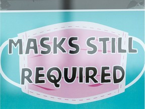 A sign reading "Masks Still Required" is seen at the Majesty and Friends store in Edmonton, on Monday, Aug. 30, 2021. Edmonton's indoor public places mask mandate will be reinstated on Friday, Sept. 3 after a council vote.