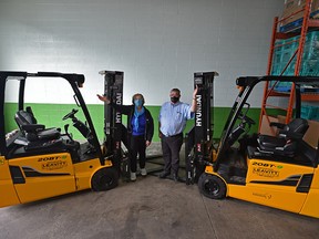 Edmonton’s Food Bank executive director Marjorie Bencz, left, and director of operations Mark Doram, on Aug. 19, 2021, accepted the delivery of two brand-new forklifts purchased through a successful community fundraiser with help from Leavitt Machinery after a call was put out for help to replace a broken forklift.