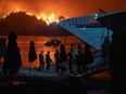 People board a ferry during evacuation as a wildfire burns in the village of Limni, on the island of Evia.