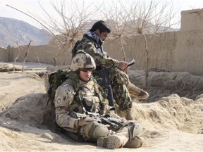 Capt. Eric Bouchard of the Canadian Operational Mentor and Liasion Team confers with an Afghan platoon commander during a foot patrol through a village in the central Panjwaii district in Afghanistan on Feb. 18, 2011.