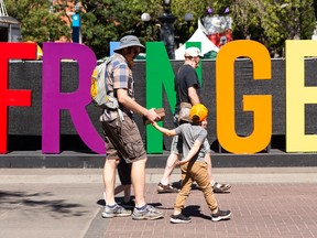 Three generations of Whyte familty members — father Nathan, sons Eli , 5, and Finn, 3, and grandfather Doug — walk past a sign for the 2021 Edmonton International Fringe Festival in Old Strathcona on Aug. 13, 2021. The festival, which features live and digital theatre performances, runs through Aug. 22.
