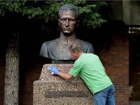 A volunteer scrubs spray paint off the Roman Shukhevych statue at the Ukrainian Youth Unity Complex, 9615 153 Ave., in Edmonton Tuesday Aug. 10, 2021.