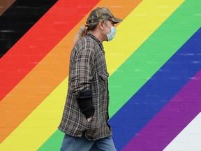 A pedestrian, wearing a protective COVID-19 face mask, makes their way along 109 Street near 82 Avenue, in Edmonton Tuesday Aug. 31, 2021. Photo by David Bloom