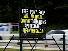 Motorists speed past a sign for free horse poop near the entrance to the Whitemud Equine Center in Edmonton on September 3, 2021.
