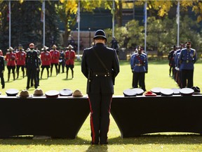 Const. Ernest Corbin with the Calgary police service stands in front of the a table with headgear representing the fallen officers in Alberta as part of the 23rd annual Police and Peace Officers Memorial Day ceremony on Sunday, Sept. 26, 2021 in Edmonton.