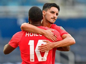 Canada's forward Junior Hoilett (left) is hugged by teammate Canada's midfielder Stephen Eustaquio after Hoilett scored a penalty kick against Haiti during their CONCACAF Gold Cup match on July 15, 2021 at Children's Mercy Park in Kansas City, Kansas.