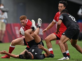 Canada's Connor Braid (L) attempts to carry the ball past New Zealand's Andrew Knewstubb (bottom) in the men's quarter-final rugby sevens match between New Zealand and Canada during the Tokyo 2020 Olympic Games at the Tokyo Stadium in Tokyo on July 27, 2021.