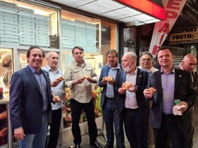 Brazil's President Jair Bolsonaro (3d L) eats pizza with Caixa Economica Federal Bank President Pedro Guimaraes, General Luiz Eduardo Ramos, Tourism Minister Gilson Machado Neto, Health Minister Marcelo Queiroga and other politicians on a street ahead of the United Nations General Assembly in New York City, U.S. September 19, 2021.