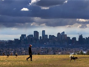 FILE - Storm clouds move in over walkers in Edworthy Park and the downtown Calgary skyline on Tuesday, May 4, 2021.