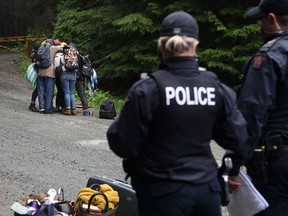 Protesters embrace as police look on during an ongoing blockade against old-growth logging in the Fairy Creek on May 24, 2021.