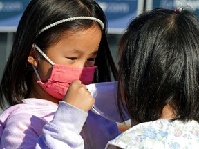 Tessa Ng (left, 5) helps her friend Liv Leong (5) put on a face mask during the COVID-19 pandemic in Edmonton. The Alberta government announced new pandemic restrictions in the province on September 3, 2021 that mandates face masks in all indoor public places, a curfew on liquor sales and an offer of $100 to unvaccinated people who get a COVID-19 vaccine, in an effort to curb a fourth-wave surge of the virus. (PHOTO BY LARRY WONG/POSTMEDIA)