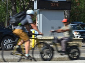 The heat wave continues as this sign reads 33º C as cyclists cruise by along 83 Ave. in Edmonton, July 13, 2021.