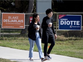 Pedestrians make their way past signs for Edmonton Griesbach Federal election candidates Blake Desjarlais and Kerry Diotte, near 70 Street and 112 Avenue in Edmonton, Tuesday Sept. 7, 2021. Photo by David Bloom
