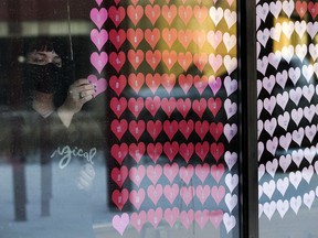 Sara Edwards adds more paper hearts, one for every Albertan who has died from COVID-19, to a memorial at All Saints' Anglican Cathedral in Edmonton on Jan. 29, 2021.