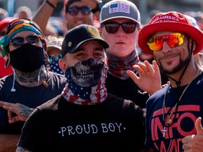 Supporters wearing Proud Boy clothing wave to the camera during a Make America Great Again campaign rally in Tampa, Fla. on Oct. 29, 2020.