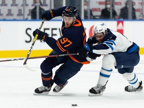 Edmonton Oilers' Connor McDavid (97) battles Winnipeg Jets' Dylan DeMelo (2) during the first period of NHL North Division playoff action at Rogers Place in Edmonton, on Wednesday, May 19, 2021. Photo by Ian Kucerak