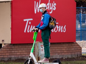 An e-scooter rider wears a COVID-19 masks while traveling in downtown Edmonton, on Thursday, Sept. 16, 2021. Photo by Ian Kucerak