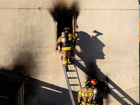 Edmonton Fire Rescue Services firefighters put out a fire in a building in an alley near 101 Street and 105A Avenue in Edmonton, on Thursday, Oct. 14, 2021. Photo by Ian Kucerak