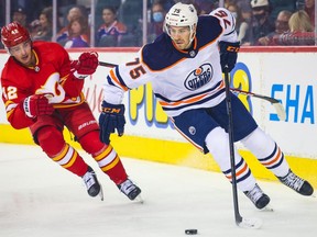 Edmonton Oilers defenceman Evan Bouchard controls the puck against Calgary Flames centre Glenn Gawdin during the first period at Scotiabank Saddledome.