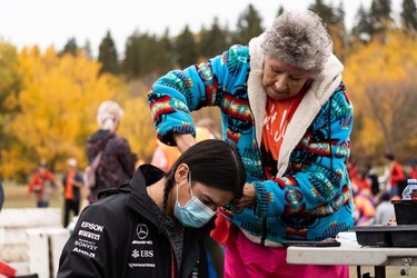 Elder Elsie Paul cuts a young man's hair (who did not give his name) during the Roots for Trees Plant Giveaway at Hawrelak Park in Edmonton, on Thursday, Sept. 30, 2021. Edmontonians were invited to pick up a plant, speak with an Elder and plant their tree or plant as an act of reconciliation on National Day of Truth and Reconciliation.