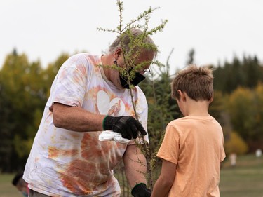 Kazim Telfer (right), 9, picks his tree with the help of Mark Otto from the City of Edmonton during the Roots for Trees Plant Giveaway at Hawrelak Park in Edmonton, on Thursday, Sept. 30, 2021. Edmontonians were invited to pick up a plant, speak with an Elder and plant their tree or plant as an act of reconciliation on National Day of Truth and Reconciliation.