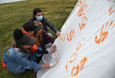 Kimberly Worth with her children Julia, 13, Jeremy, 11 and Rachel, 9, painting a tipi covering it with their orange handprints on the first National Day for Truth and Reconciliation at the Westridge Community Park where they held teachings, drumming, and songs in Edmonton, September 30, 2021.