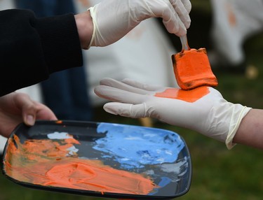 Participants get their gloved hand painted to cover a tipi with their orange handprints on the first National Day for Truth and Reconciliation at the Westridge Community Park where they held teachings, drumming, and songs in Edmonton, September 30, 2021.