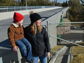 Katrina Maximchuk with her son, Peter, 5, is sounding the alarm along with other residents about the low height of the concrete barrier running along the south side of the refurbished Ada Boulevard bridge, Wednesday, Oct. 13, 2021.