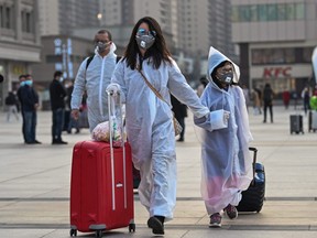 People wearing protective clothing and masks arrive at Hankou Railway Station in Wuhan, to board one of the first trains leaving the city in China's central Hubei province, April 8, 2020.