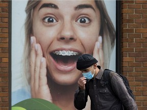 A pedestrian adjusts their COVID-19 face mask as they make their way along 109 Street near 106 Avenue in Edmonton, Tuesday Sept. 28, 2021.