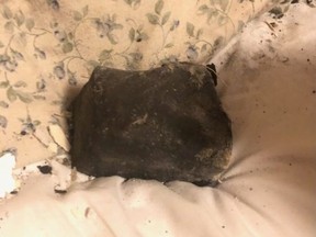A meteorite rests on a bed inside a residential building in Golden, B.C., in an undated handout photo. Ruth Hamilton says she was sound asleep on Oct. 4 when she was awakened by her dog barking, the sound of a crash through her ceiling and the feeling of debris on her face.