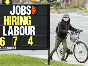 A woman checks out a jobs advertisement sign during the COVID-19 pandemic in Toronto on April 29, 2020.
