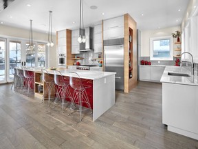 A bright pop of red on the island makes this kitchen vibrant, by Birkholz Homes.