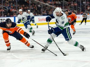 Edmonton Oilers' Cody Ceci (5) battles Vancouver Canucks' Jason Dickinson (18) at Rogers Place in Edmonton on Oct. 7, 2021.