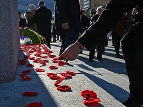 People lay their poppies at the base of the cenotaph after the Remembrance Day ceremony held at city hall in Edmonton on Nov. 11, 2021.