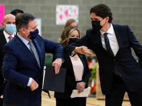 Prime Minister Justin Trudeau (right) and Alberta Premier Jason Kenney bump elbows during a joint federal-provincial announcement of $10-a-day daycare at Boyle Street Plaza in Edmonton, on Monday, Nov. 15, 2021.
