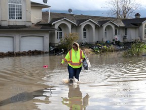 A resident of the Yarrow neighbourhood wades through floodwaters outside her home after rainstorms caused flooding and landslides in Chilliwack, B.C., Nov. 20, 2021.