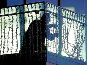 An Alberta government employee puts up some Christmas lights on a second floor balcony at the Federal Building in Edmonton on November 23, 2021. (PHOTO BY LARRY WONG/POSTMEDIA)