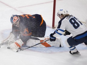 Edmonton Oilers goalie Stuart Skinner (74) covers the puck from Winnipeg Jets Kyle Connor (81) during second period NHL action on Thursday, Nov. 18, 2021 in Edmonton.