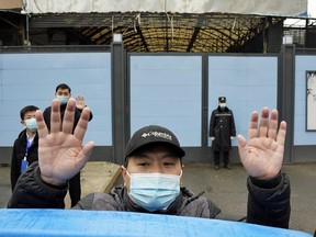 A security guard waves for journalists to clear the road after a convoy carrying the World Health Organization team entered the Huanan Seafood Market in Wuhan in central China's Hubei province on Sunday, Jan. 31, 2021.