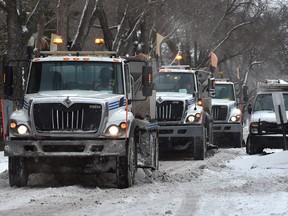 A trio of city plows/salt trucks navigate along narrow streets in the downtown as a snow storm sweeps through Edmonton, November 16, 2021. Ed Kaiser/Postmedia